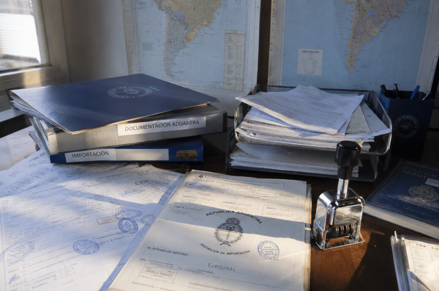 Documentos aduaneros, sellos oficiales y mapas del Cono Sur sobre escritorio, sin personas en primer plano